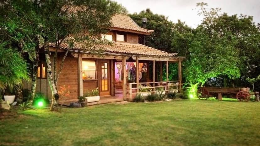 A cabana do Mirador ao entardecer, com as luzes acesas e o gramado à frente